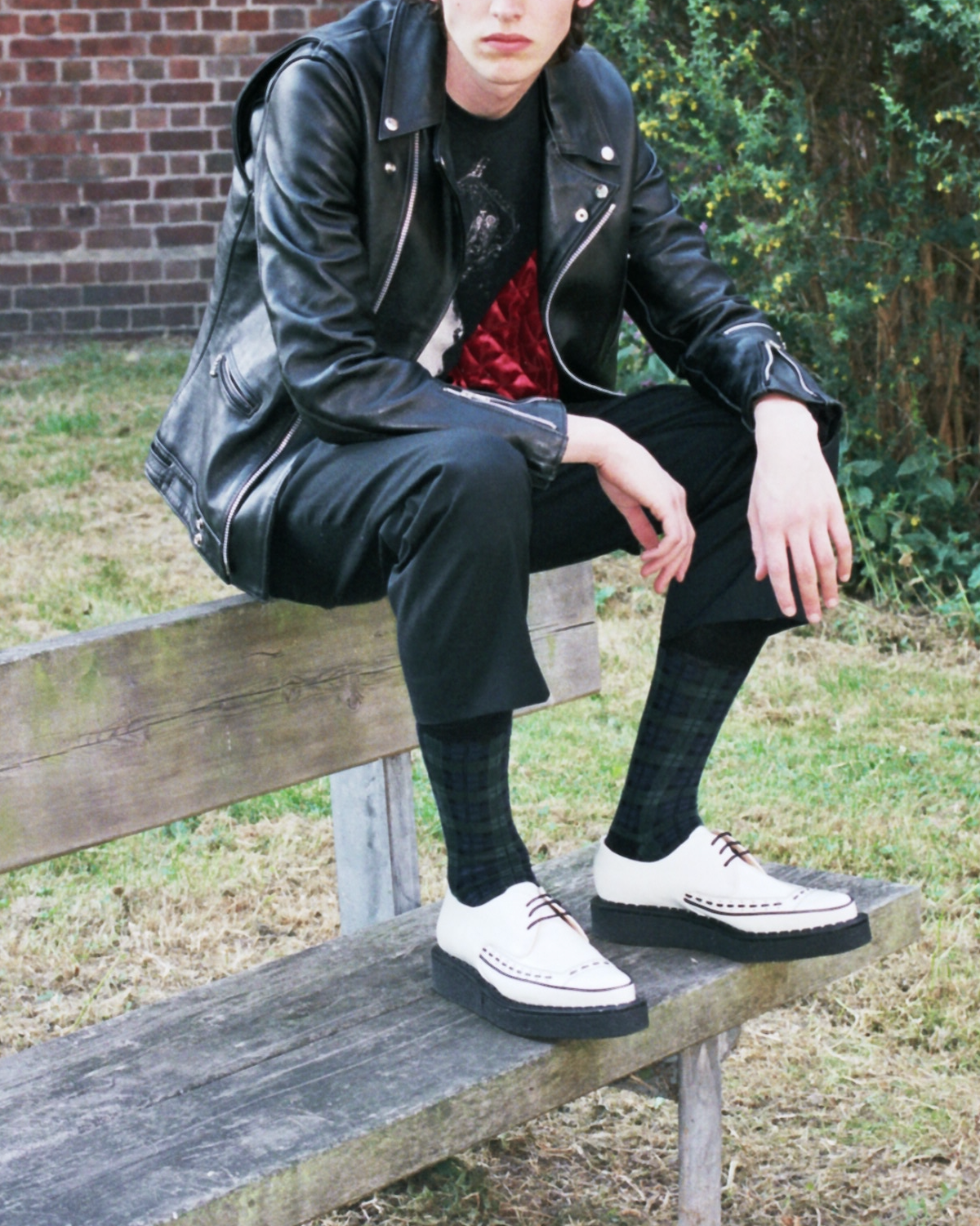 Punk sitting on park bench wearing white Diano Creeper